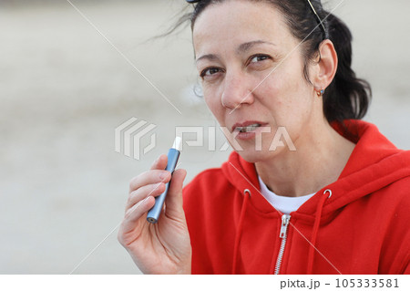 Electronic cigarette technology. Adult woman smokes hybrid cigarette device with real tobacco refills and heating pad, tobacco heating system. Technology between analog and electronic cigarettes 105333581