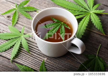 Tea with cannabis leaves on wooden table 105333696
