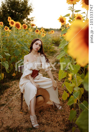 Woman in a dress in a field of sunflowers on a chair 105333747