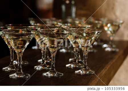 Martini glasses stand on a wooden stand. Martini glasses are on the bar. clean glasses with alcohol. selective focus Martini glasses stand on a wooden stand. Martini glasses are on the bar. clean glasses with alcohol. selective focus 105333956