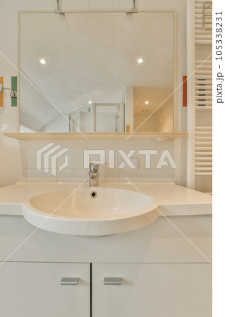 a white bathroom with a sink and mirror in the corner on the wall above it is a towel rack that has been used for 105338231