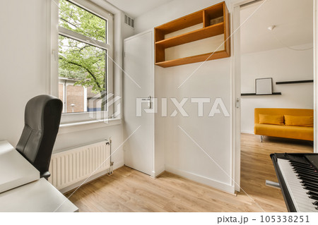 a small room with a piano in the corner and an open door leading to another room on the other side 105338251
