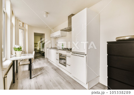 a kitchen and dining area in an apartment with white cabinets, wood flooring and light gray wallpapers 105338289