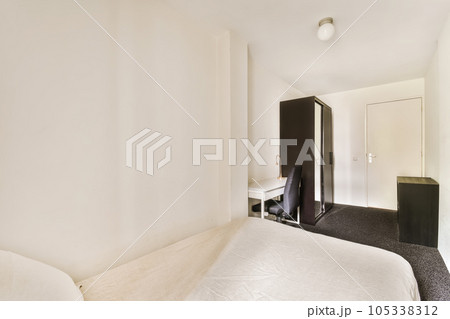 a bedroom with a white bed and black cabinetd cupboards on the wall in the room is very clean a bedroom with a white bed and black cabinetd cupboards on the wall in the room is very clean 105338312