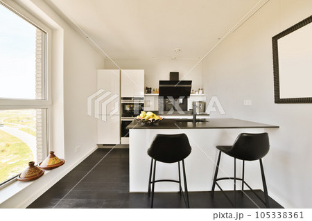 a kitchen with two stools in front of the counter and window looking out onto the street from the living room a kitchen with two stools in front of the counter and window looking out onto the street from the living room 105338361