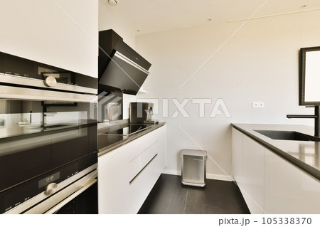 a kitchen with white cabinets and black counter tops on the counters in front of the oven is an appliance a kitchen with white cabinets and black counter tops on the counters in front of the oven is an appliance 105338370