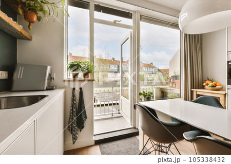 a kitchen and dining area in a small apartment with sliding glass doors leading out onto the terraced courtyards a kitchen and dining area in a small apartment with sliding glass doors leading out onto the terraced courtyards 105338432
