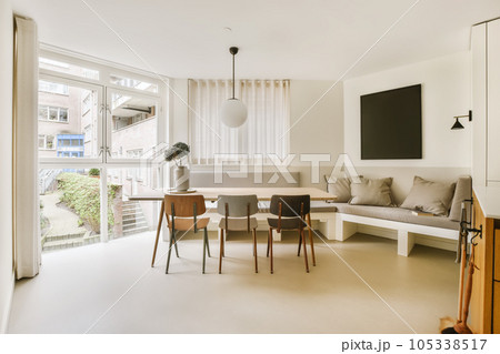 a living room with a couch, table and television on the wall in it's corner window looking out onto the street 105338517