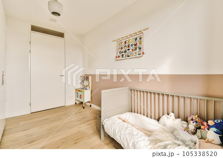 a child's room with white walls and wood flooring, including a cribt bed in the corner a child's room with white walls and wood flooring, including a cribt bed in the corner 105338520
