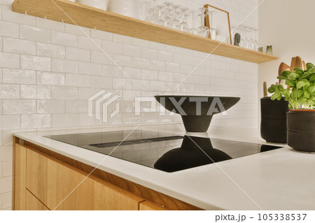a kitchen with white tiles on the wall and wood cabinets in the counter tops are made out of black granite a kitchen with white tiles on the wall and wood cabinets in the counter tops are made out of black granite 105338537