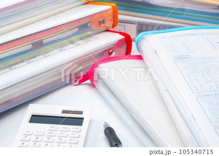 山積みの書類ファイルと電卓とボールペン 105340715