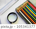 白い用紙の上に置かれた、カラフルな色鉛筆と虫眼鏡と定規 105341377