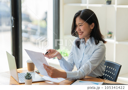 young businesswoman sits at a table and reads a document in office young businesswoman sits at a table and reads a document in office 105341422