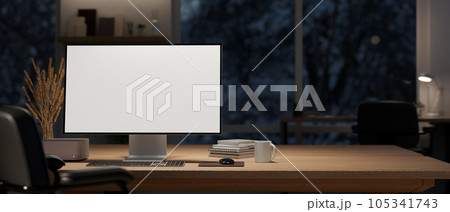 A computer mockup and decor on a wooden table in a modern dark office room at night. A computer mockup and decor on a wooden table in a modern dark office room at night. 105341743
