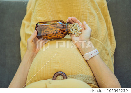 Prenatal Vitamins. Portrait Of Beautiful Smiling Pregnant Woman Holding Transparent Glass Jar With Pills, Taking Supplements For Healthy Pregnancy While Sitting On Couch At Home, Free Space Prenatal Vitamins. Portrait Of Beautiful Smiling Pregnant Woman Holding Transparent Glass Jar With Pills, Taking Supplements For Healthy Pregnancy While Sitting On Couch At Home, Free Space 105342239