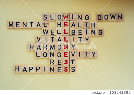 Top view of WELLNESS word on yellow background. Minimalism creative crossword puzzle concept. Message of text Slowing down mental health wellbeing vitality harmony longevity rest happiness 105342899