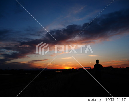 埼玉県川口市荒川堤からの風景（夕焼け空に向かって走る人） 105343137