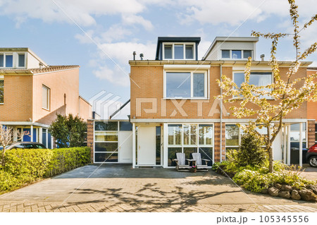 an outside view of a house with trees and cars parked in the driveway, on a sunny day - stock photo 105345556