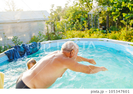 Grandpa and granddaughter play and have fun in the pool.  105347601