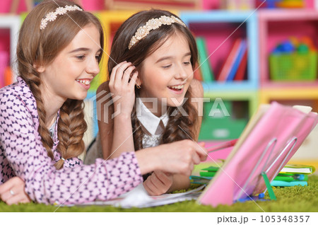 Two school age kids doing their homework on floor at home. Brother and sister siblings children drawing together, preparing for school lesson. Homeschool concept. Two school age kids doing their homework on floor at home. Brother and sister siblings children drawing together, preparing for school lesson. Homeschool concept. 105348357