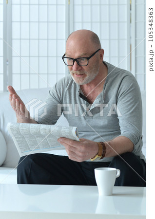 Senior old man reading newspaper at home 105348363