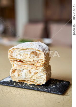 Breakfast in the cafe, morning coffee. Cappuccino and dessert Napoleon on the table. 105348645