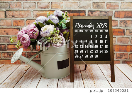 November 2023 monthly calendar with green leaf decoration on wooden background 105349081