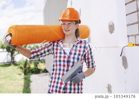 The woman with rolls of reinforcing fiberglass. Insulation of the house with polyfoam board on the facade The woman with rolls of reinforcing fiberglass. Insulation of the house with polyfoam board on the facade 105349176
