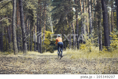 woman cyclist rides in the forest on a mountain bike. woman cyclist rides in the forest on a mountain bike. 105349207