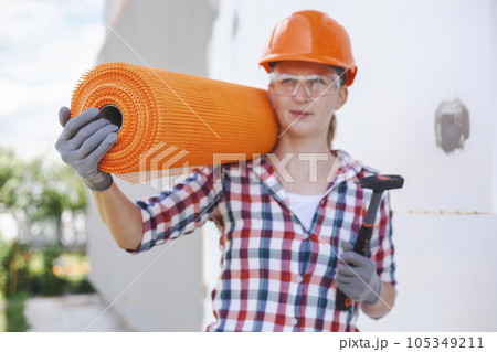 The woman with rolls of reinforcing fiberglass. Insulation of the house with polyfoam board on the facade 105349211
