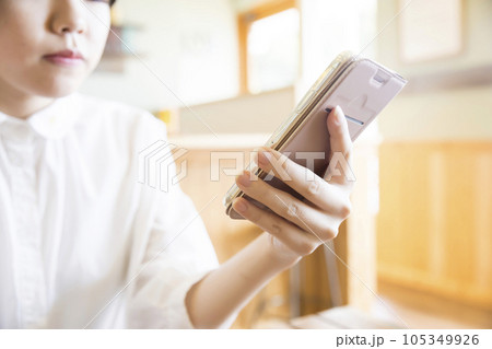 カフェでスマホを見る若い女性手元 105349926