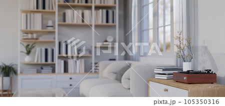 A vintage record player on a drawer by a cozy couch in a modern and cozy white living room. 105350316