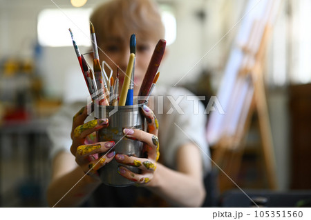 Image of male artist in apron holding metal bucket with different brushes of the artist. Art, education, creativity and people 105351560