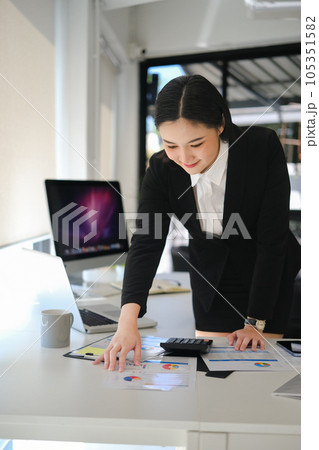 Professional businesswoman analyzing sales statistics document at office desk Professional businesswoman analyzing sales statistics document at office desk 105351582