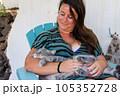 The cat lies on the lap of a young woman sitting in the garden at home. love between pet and people. 105352728