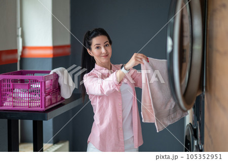 Young woman unloading washing machine in public laundry. Young woman unloading washing machine in public laundry. 105352951