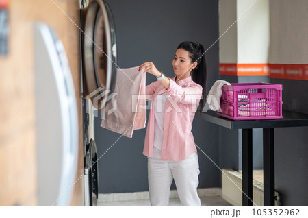 Young woman unloading washing machine in public laundry. 105352962