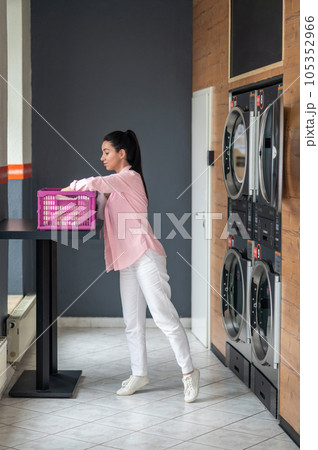 Young woman unloading washing machine in public laundry. 105352966
