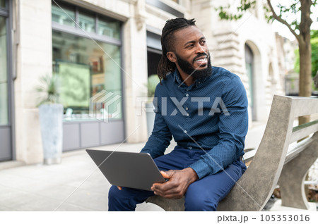 Dark-skinned man with a laptop working outside 105353016