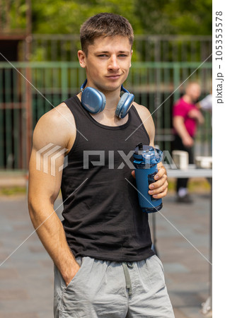 Portrait of athletic muscular man in sportswear holding drinking water bottle on workout playground Portrait of athletic muscular man in sportswear holding drinking water bottle on workout playground 105353578