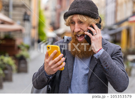 Irritated stressed business man talking on two mobile phones having conversation conflict quarrel 105353579