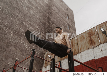 Young man doing parallel bars abdominal exercise. 105353621