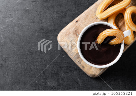 Traditional Spanish churros with hot chocolate on black slate background 105355821