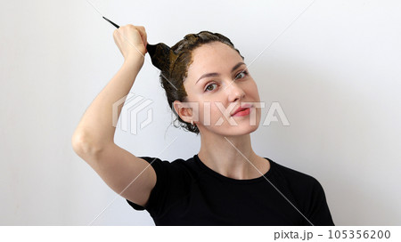 A young woman dyes her hair with an herbal mixture of henna and basma to produce a brown color A young woman dyes her hair with an herbal mixture of henna and basma to produce a brown color 105356200