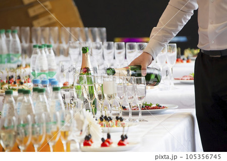 Waiter's hands pouring a drink into glasses Waiter's hands pouring a drink into glasses 105356745