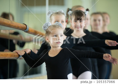 Little girls at the ballet machine. Lesson choreography. Young ballerinas.. Training of the initial group on gymnastics.Acrobatics lesson Little girls at the ballet machine. Lesson choreography. Young ballerinas.. Training of the initial group on gymnastics.Acrobatics lesson 105357066