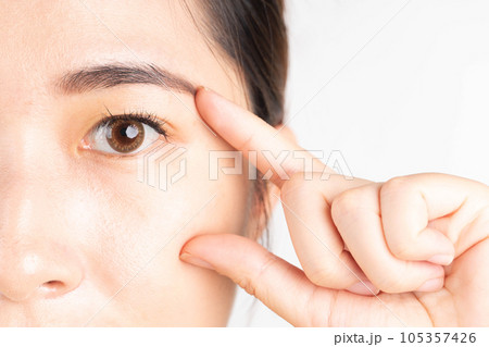 Beauty asian woman touching her healthy eyes over white background. Optimal eyes health care concept. Close up. Beauty asian woman touching her healthy eyes over white background. Optimal eyes health care concept. Close up. 105357426