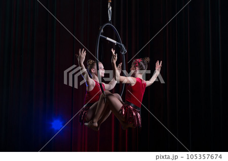 Circus actress acrobat performance. Two girls perform acrobatic elements in the air ring. 105357674