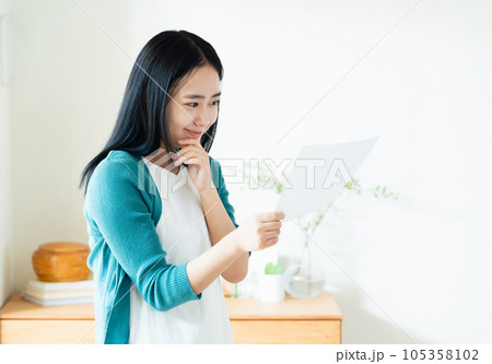 室内で書類を見る若い女性 105358102