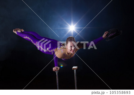 Circus actress performs the number in a beautiful smoke. Manual equilibrium on canes. Flexible girl body.Performance of an air gymnast in a circus 105358693